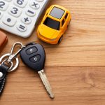 Car,Key,With,Calculator,And,Pocket,Money,On,Wood,Table